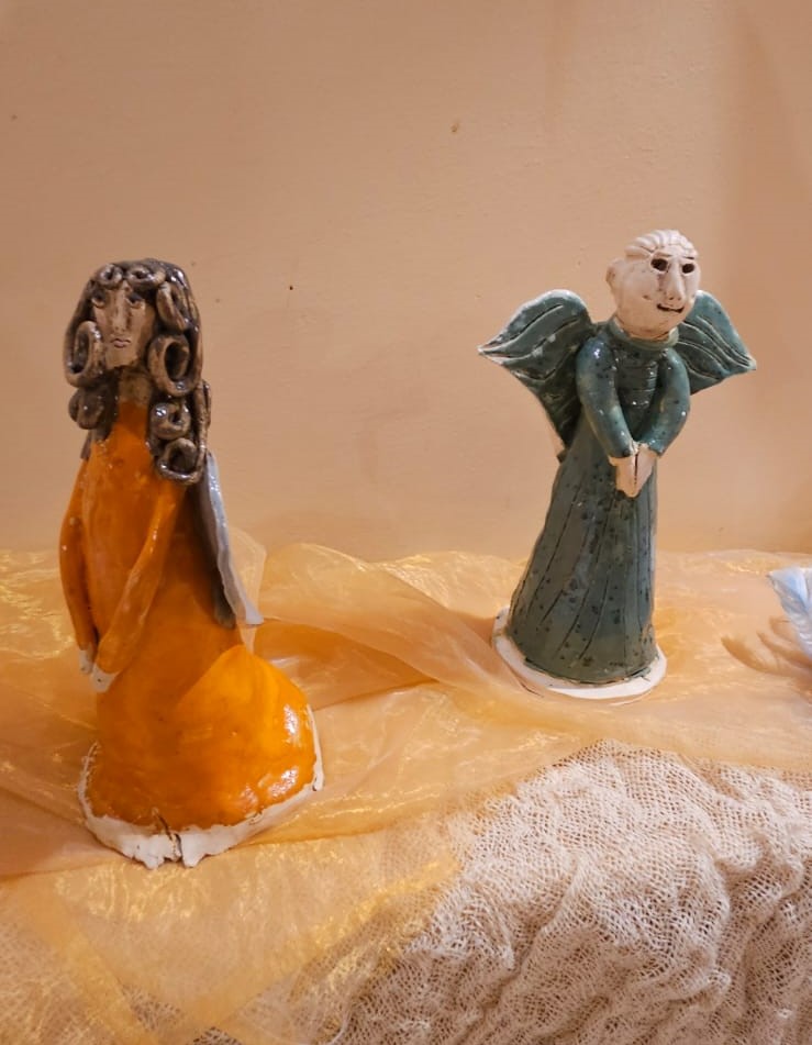 Na zdjęciu widać dwie rzeźby przedstawiające anioły w pomarańczowej i turkusowej szacie.