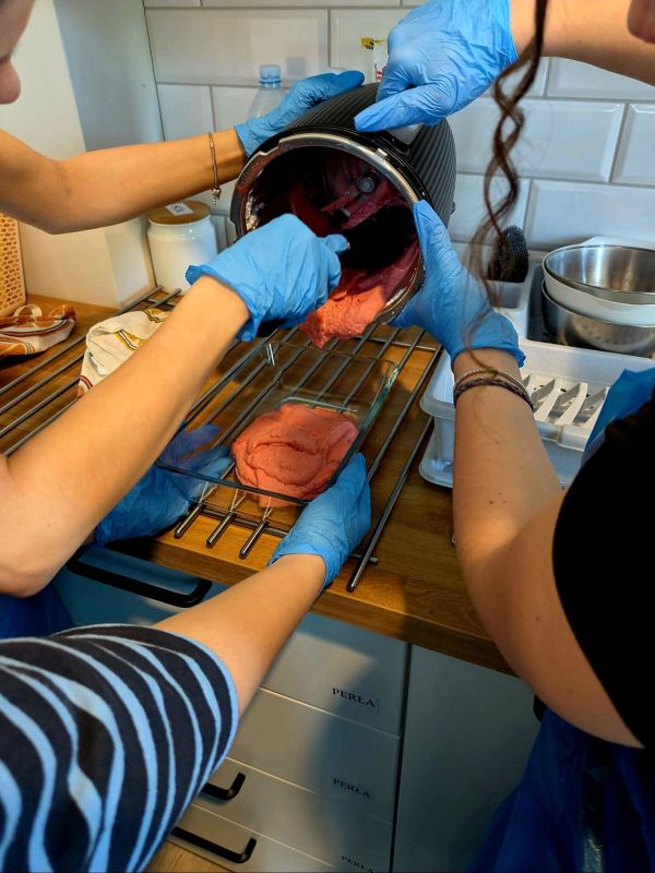 Na zdjęciu widać osoby wykładające z misy termomiksa lody truskawkowe.